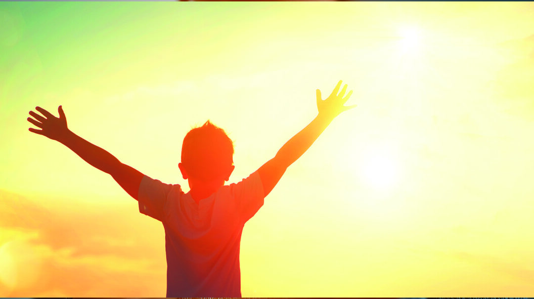 Boy hands up looking at the sun